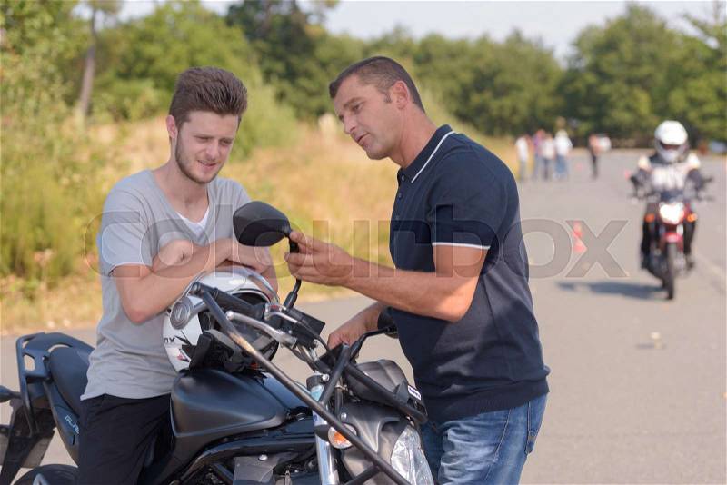 Motorbike teacher showing student how to pass, stock photo