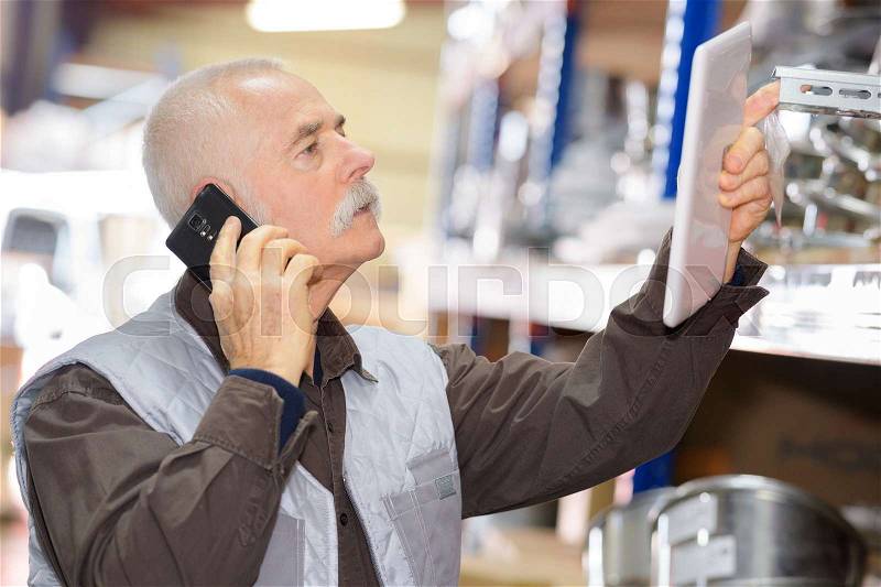 Senior man in stores with cellphone and tablet, stock photo