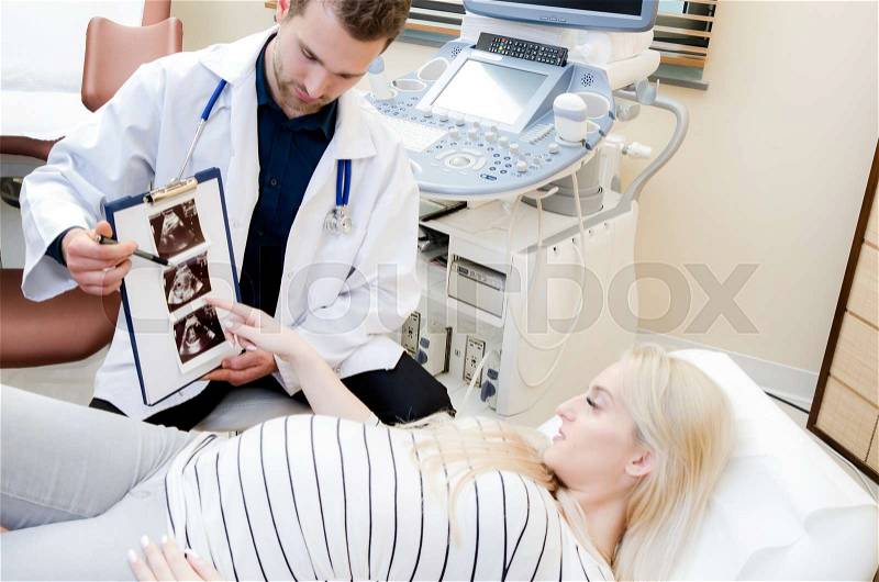 Doctor showing baby ultrasound image to pregnant woman. showing ultrasound usg pregnancy gynecologist patient pregnant concept, stock photo