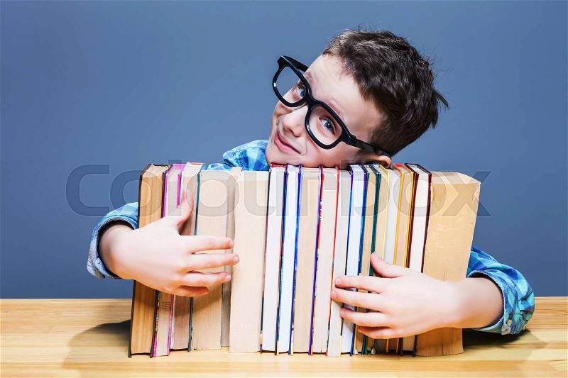 Little pupil in glasses hugs books. Education concept. Getting elementary knowledges in school, stock photo