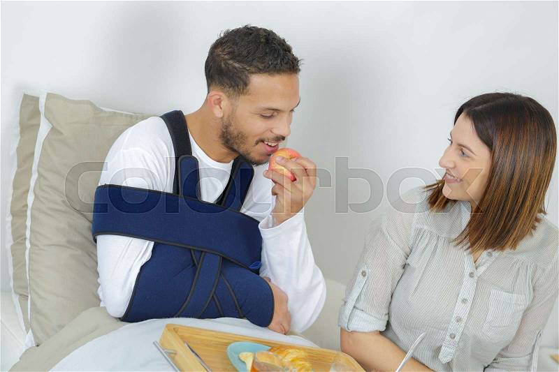 Injured man eating apple with left hand, stock photo
