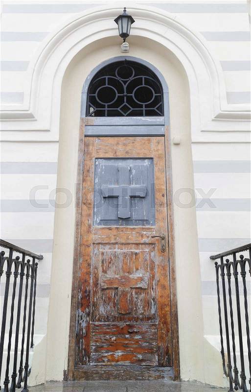 Closed wooden door with crosses in white Church wall, vertical background photo texture, stock photo