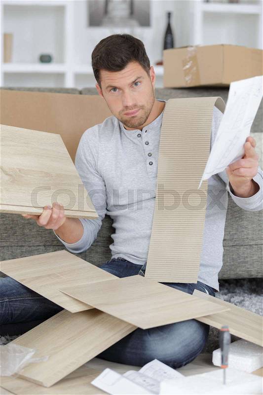 Frustrated man putting together self assembly furniture, stock photo
