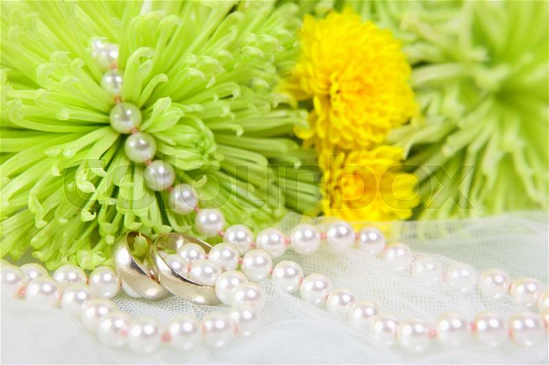 White necklace of pearls, wedding rings and bouquet of chrysanthemums on a white veil, stock photo