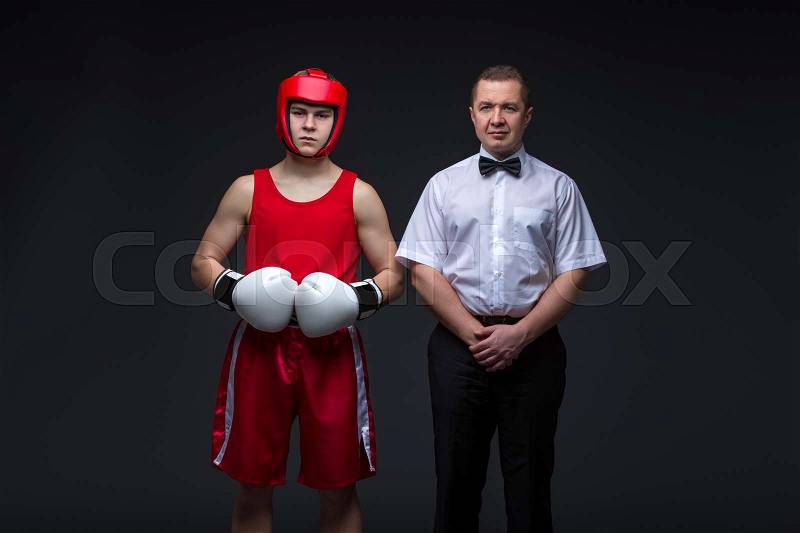 Referee and young boxing sportsman standing before fight. Studio shot on black background. Copy space, stock photo