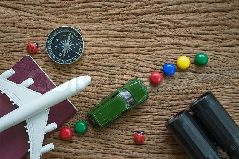 Airplane, passport, compass, binoculars and miniature car on wood table as travel planning road trip concept, stock photo