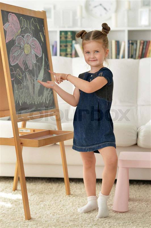 Cute little girl drawing on chalkboard, stock photo