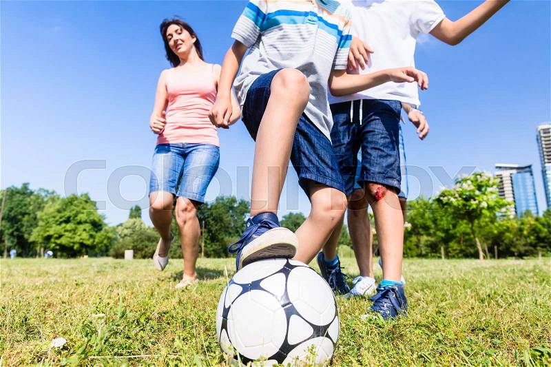 Family playing football or soccer in park in summer, stock photo