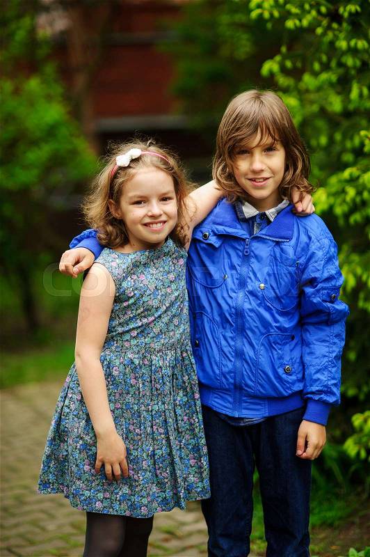 Two little friends, the boy and the girl, stand having embraced. Children smile, stock photo