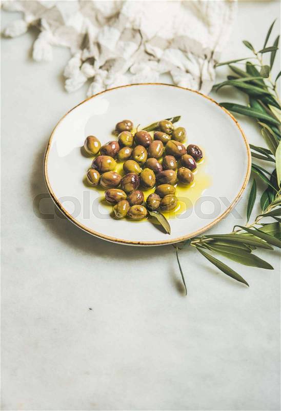 Pickled green Mediterranean olives in olive oil on white plate, stock photo