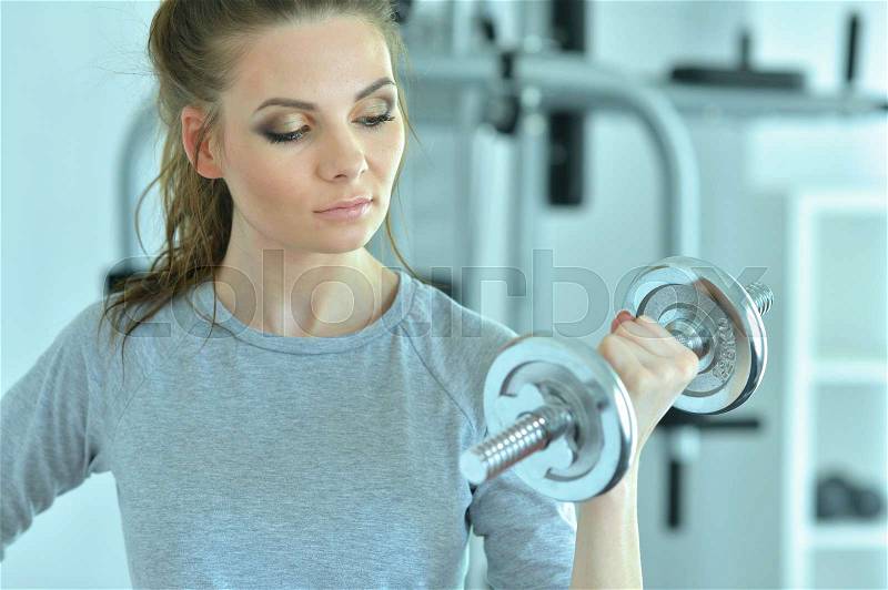 Portrait of a young woman in a gym with a dumbbell, stock photo