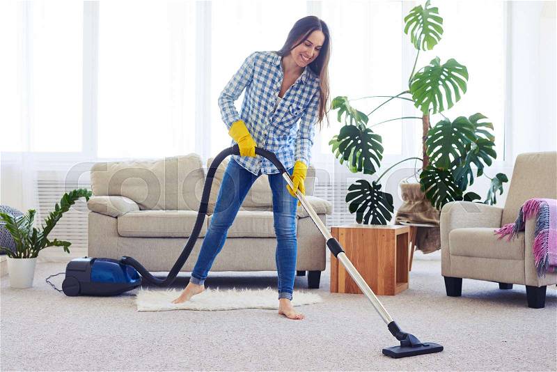 Wide shot of slim woman cleaning with vacuum cleaner carpet, stock photo