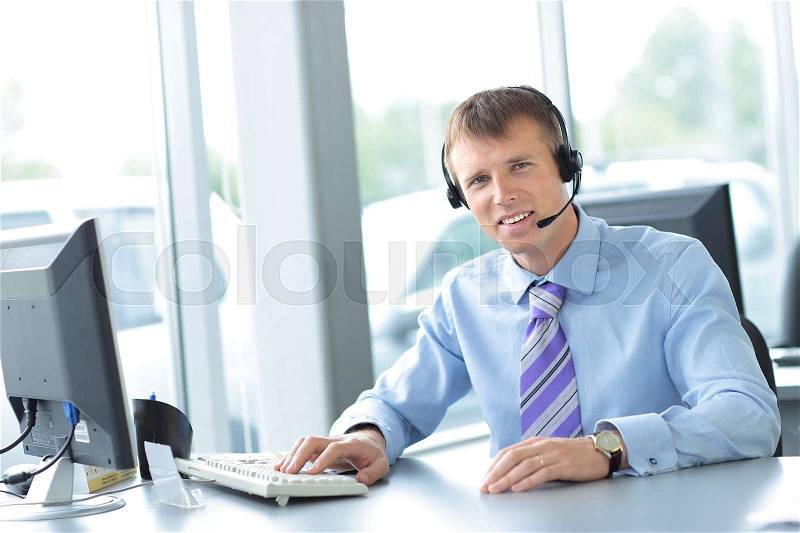 Happy young man working at callcenter, using headset, stock photo