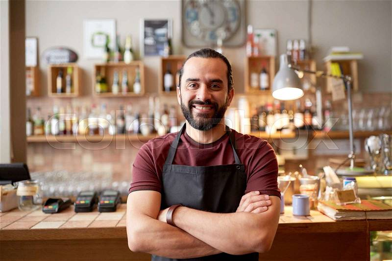 Small business, people and service concept - happy man or waiter in apron at bar or coffee shop, stock photo