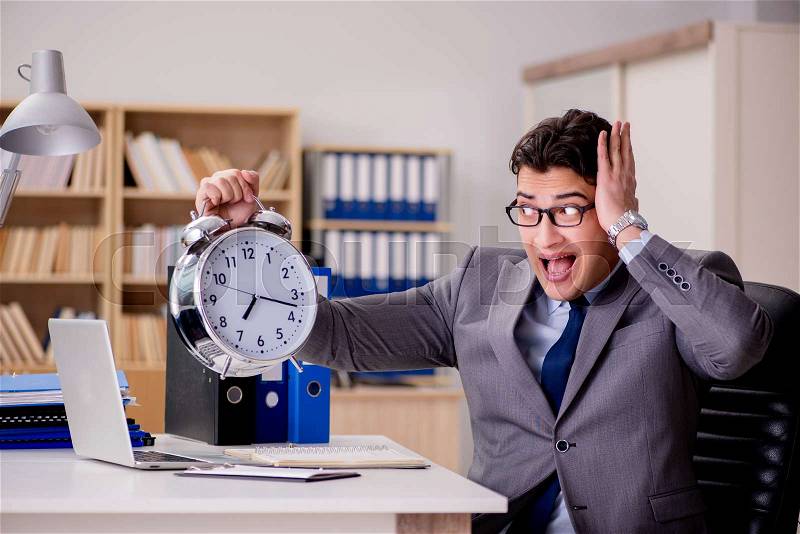 Businessman with clock failing to meet deadlines, stock photo