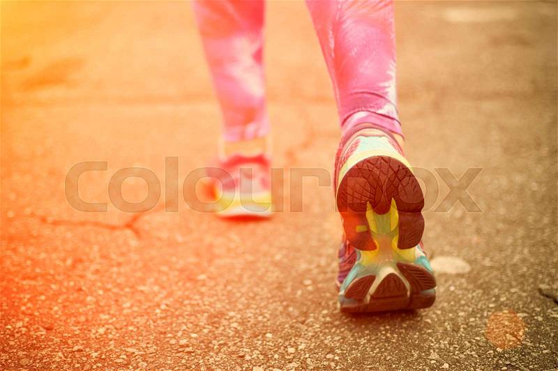 Runner feet running on road closeup on shoes. Woman fitness sunrise jog workout wellness concept, stock photo