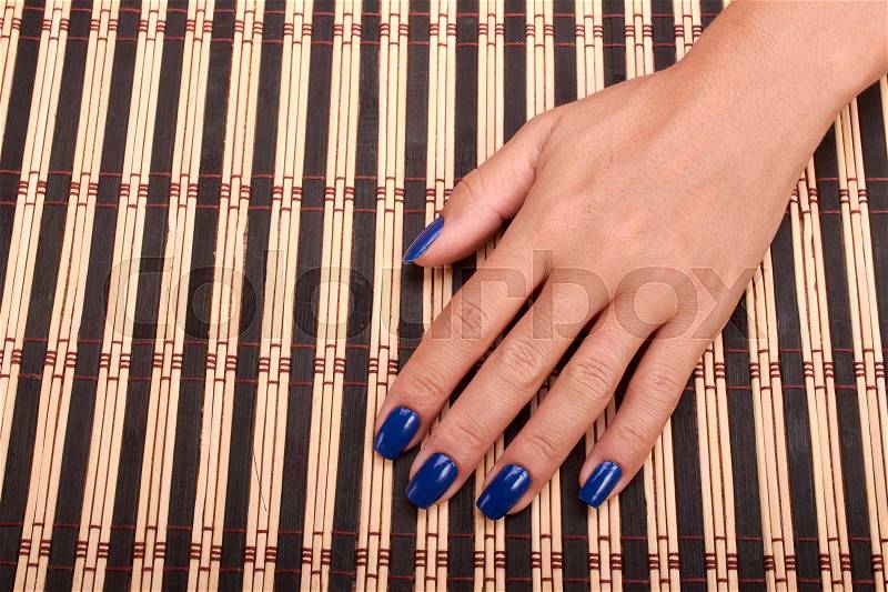 Woman hands and nails blue care of manicure in wood background, stock photo