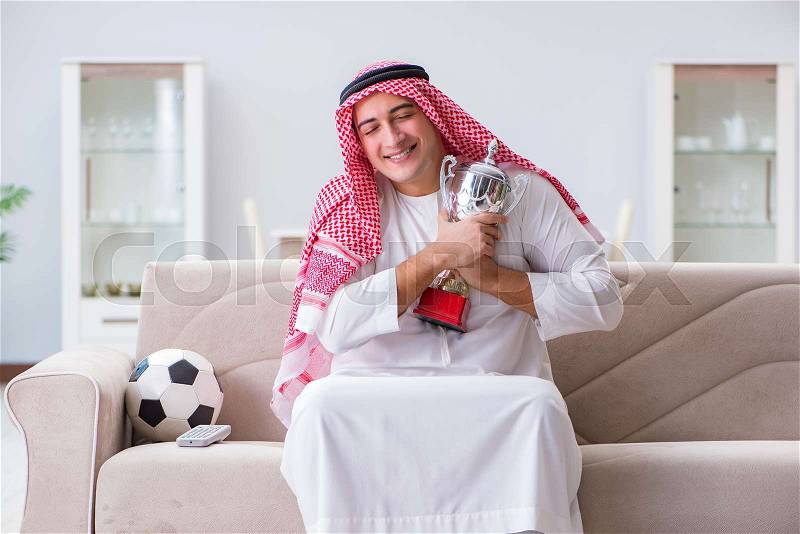 Arab man watching sport football at tv, stock photo