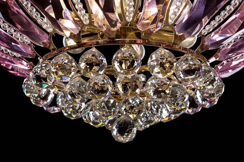 Contemporary gold chandelier isolated on black background. Crystal chandelier decorated pink crystals. close-up, stock photo