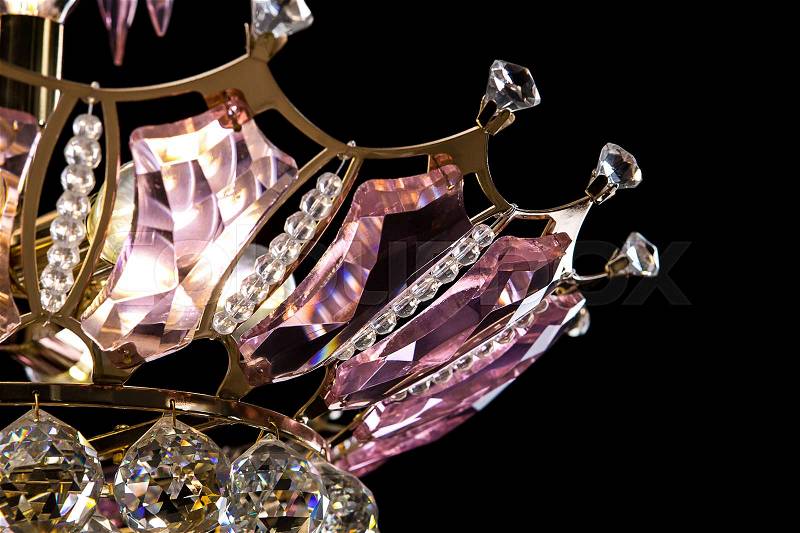 Contemporary gold chandelier isolated on black background. Crystal chandelier decorated pink crystals. close-up, stock photo