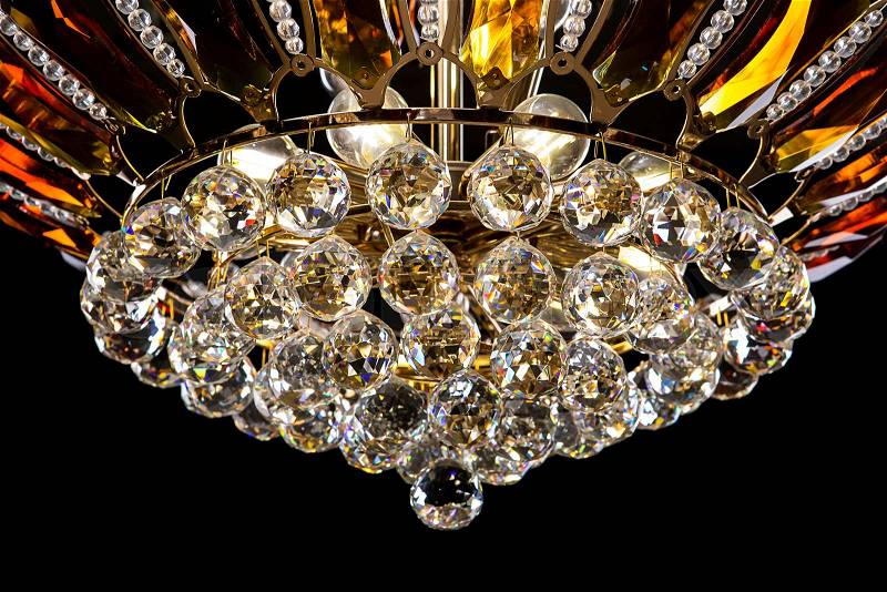 Contemporary gold chandelier isolated on black background. Crystal chandelier decorated amber crystals. close-up, stock photo