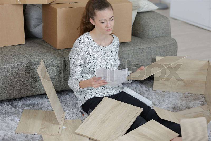 Frustrated woman putting together self assembly furniture, stock photo
