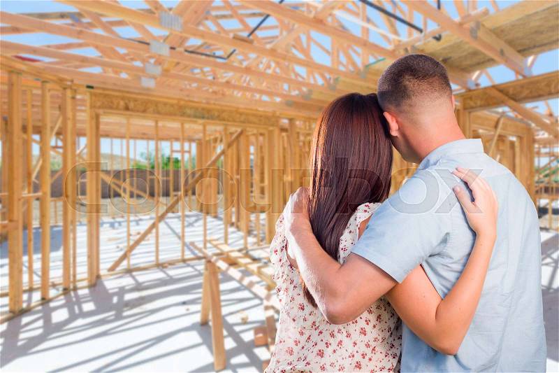 Young Military Couple On Site Inside Their New Home Construction Framing, stock photo