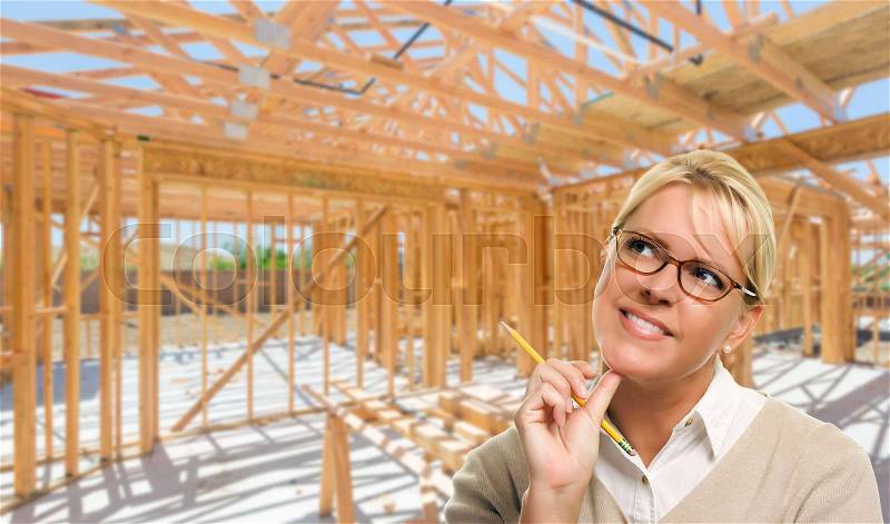 Pensive Woman with Pencil On Site Inside New Home Construction Framing, stock photo