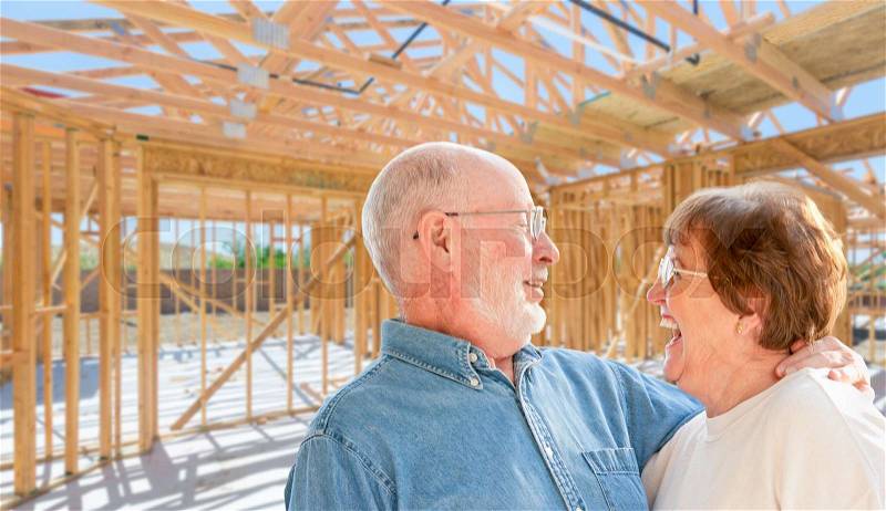 Senior Couple On Site Inside Their New Home Construction Framing, stock photo