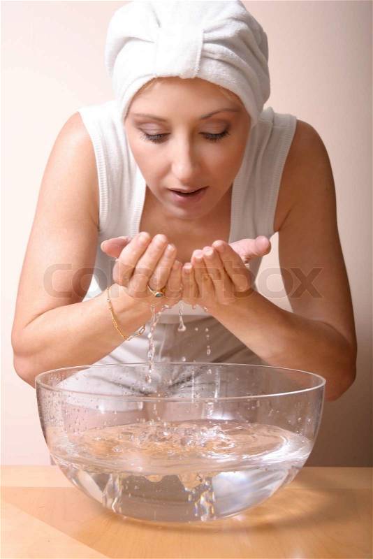A woman cleanses her face with fresh water, stock photo