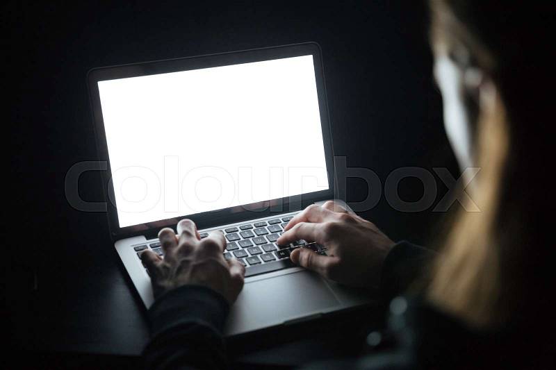 Photo of young concentrated man using laptop computer at home indoors at night. Looking at laptop display, stock photo