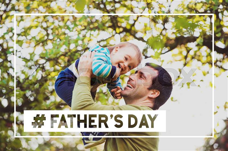 Young father holding his little son, lifting him in the air against green tree. Fathers day hashtag, stock photo