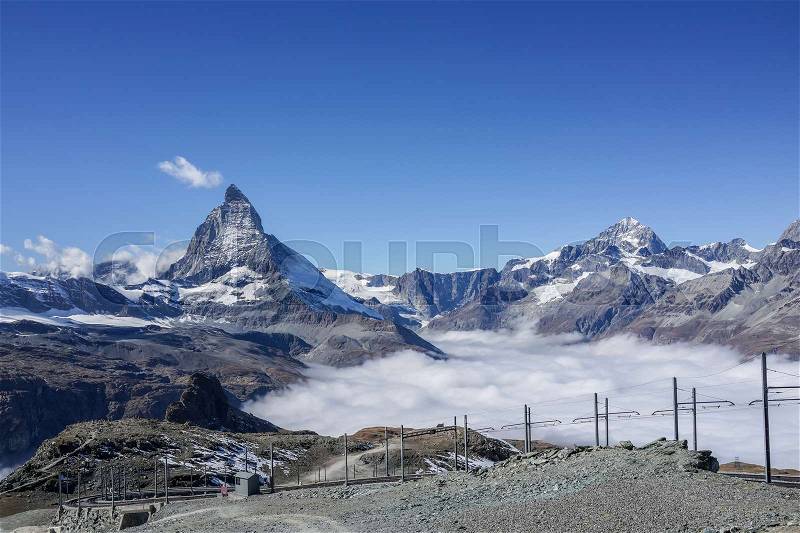 Beautiful iconic mountain Matterhorn with clear blue sky and mist below, Zermatt, Switzerland, stock photo