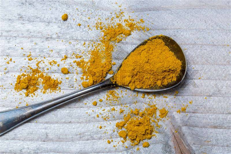 Curry powder on a spoon macro, stock photo