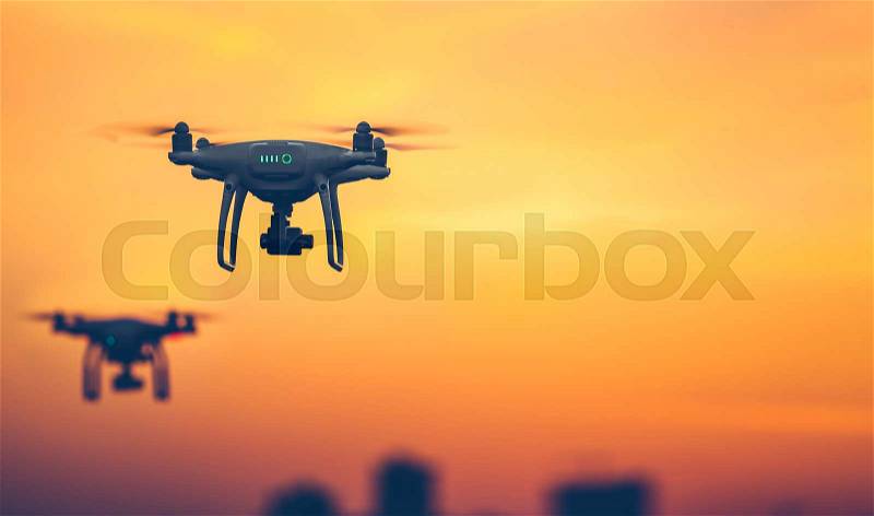 Two Professional Remote Control Air Drones with action camera flying in dramatic sunset sky. Modern technologies. Travel, hobby, inspiration. Pastel orange toning. Horizontal copy space. Kiev, Ukraine, stock photo