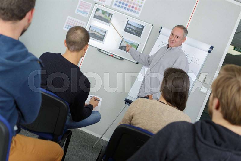 Teacher stood in front of college class, stock photo