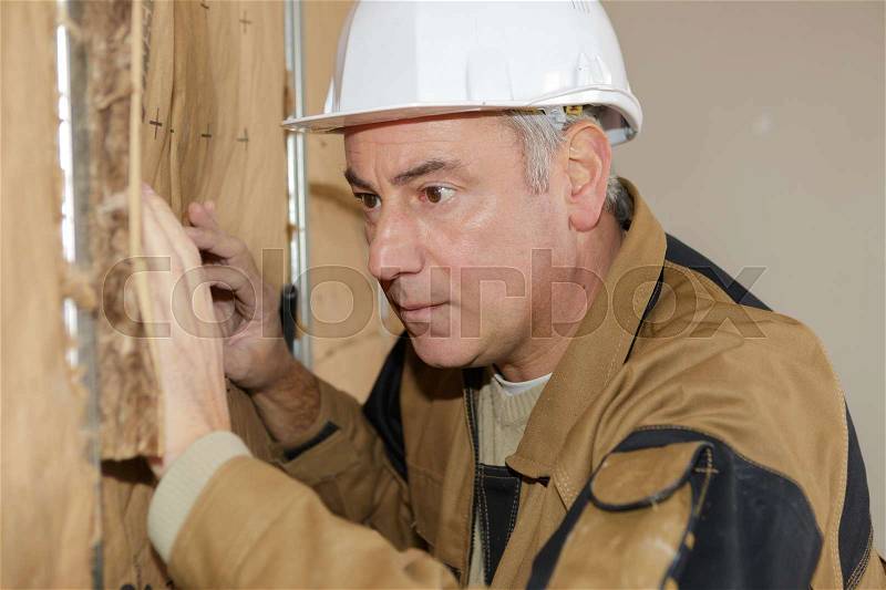 Plasterer worker at a indoors wall insulation works, stock photo