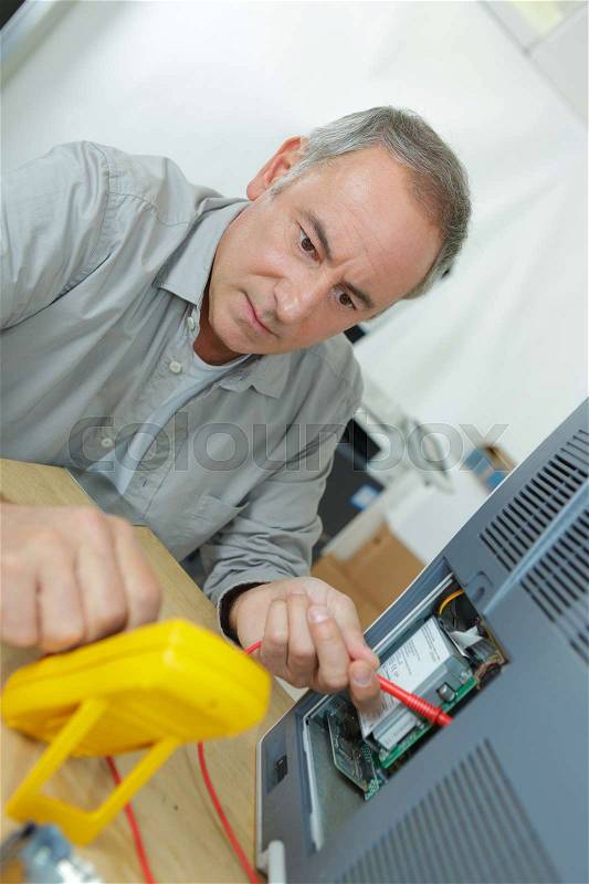 Senior technician using multi meter to test electrical appliance, stock photo