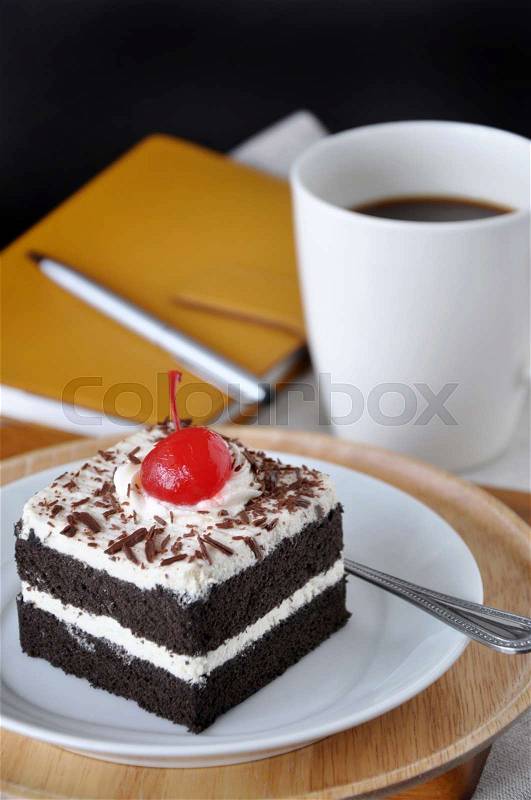 Black Forest Cake with yellow notebook and cup of coffee on background, stock photo
