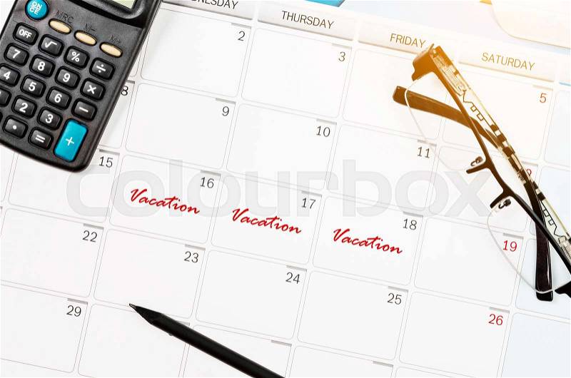 Mark long vacation on calendar with eyeglasses and calculator, stock photo