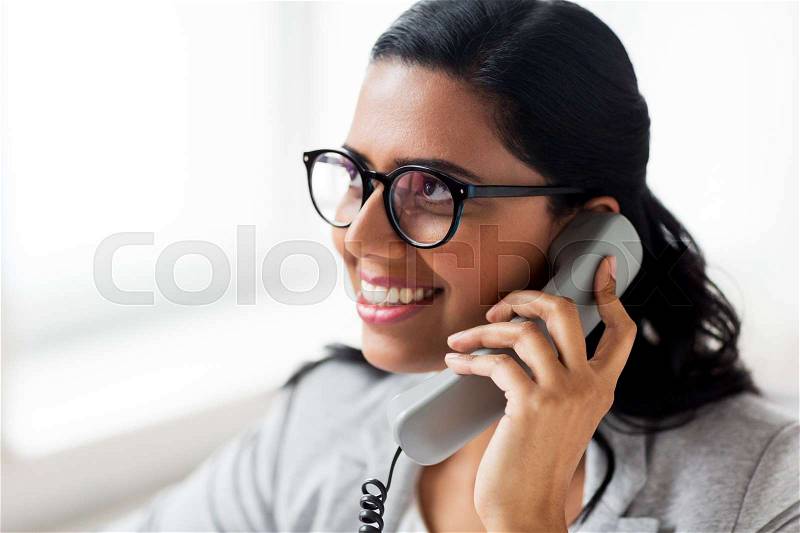 Business, technology, communication and people concept - happy smiling businesswoman or secretary calling on phone at office, stock photo