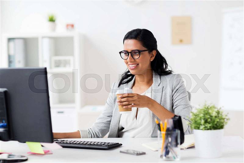 Business, people, work and technology concept - happy businesswoman with computer drinking coffee from paper cup at office, stock photo