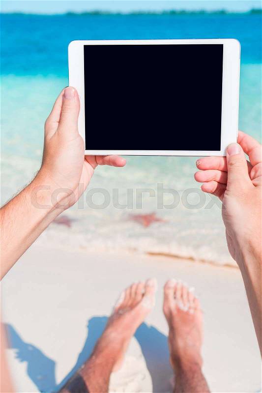Closeup laptop in male hands on the background of turquoise ocean at tropical beach, stock photo