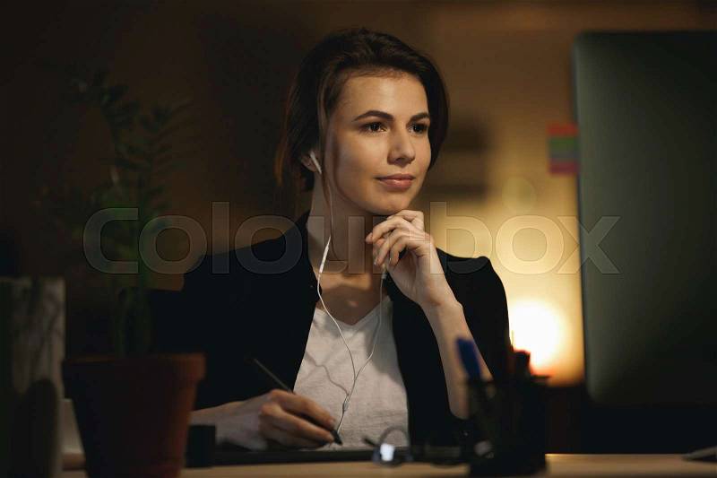 Woman designer working and listening music with headphones in office, stock photo