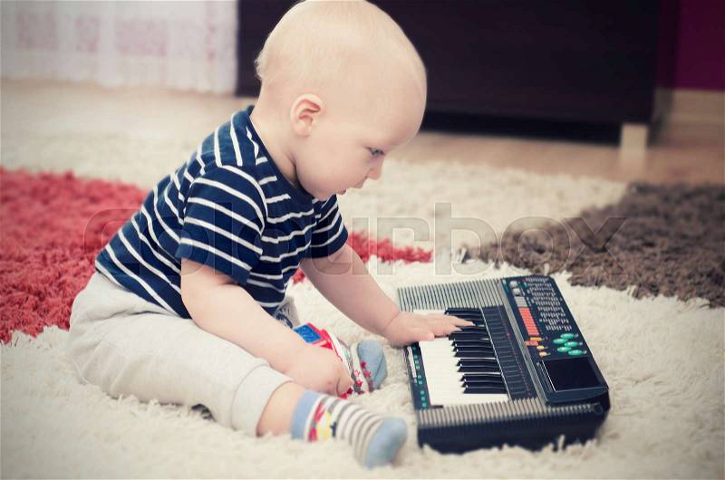 Little baby boy plays on keyboard toy. baby piano music playing child white cute little concept, stock photo