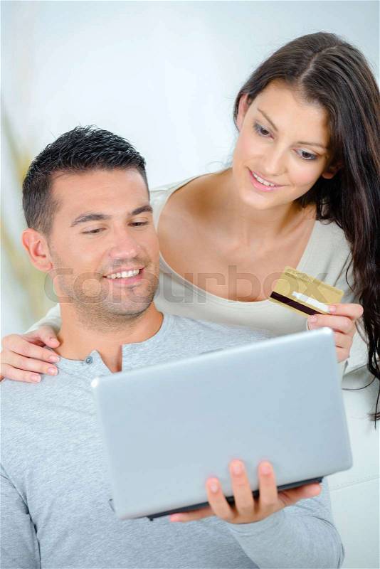 Couple looking at laptop and holding a credit card, stock photo
