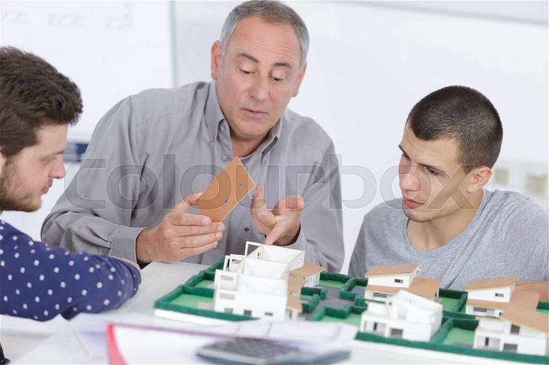 Men in discussion around model housing development, stock photo