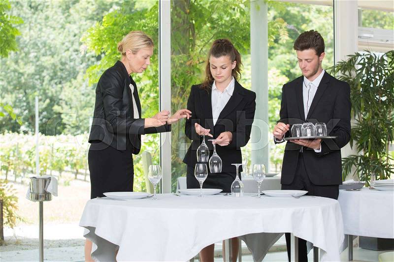 Manager teaching waiting staff with wineglasses, stock photo