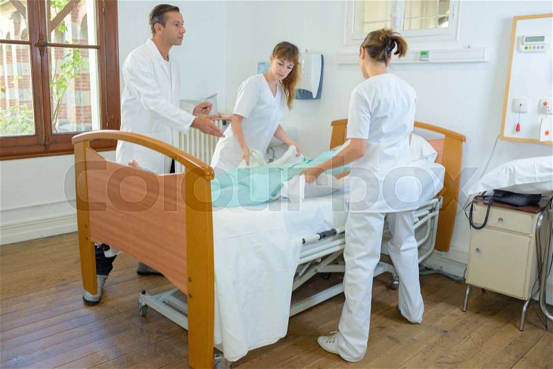 Nurses lifting patient under doctor\'s supervision, stock photo