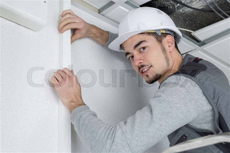 Man fitting cable trunking, stock photo